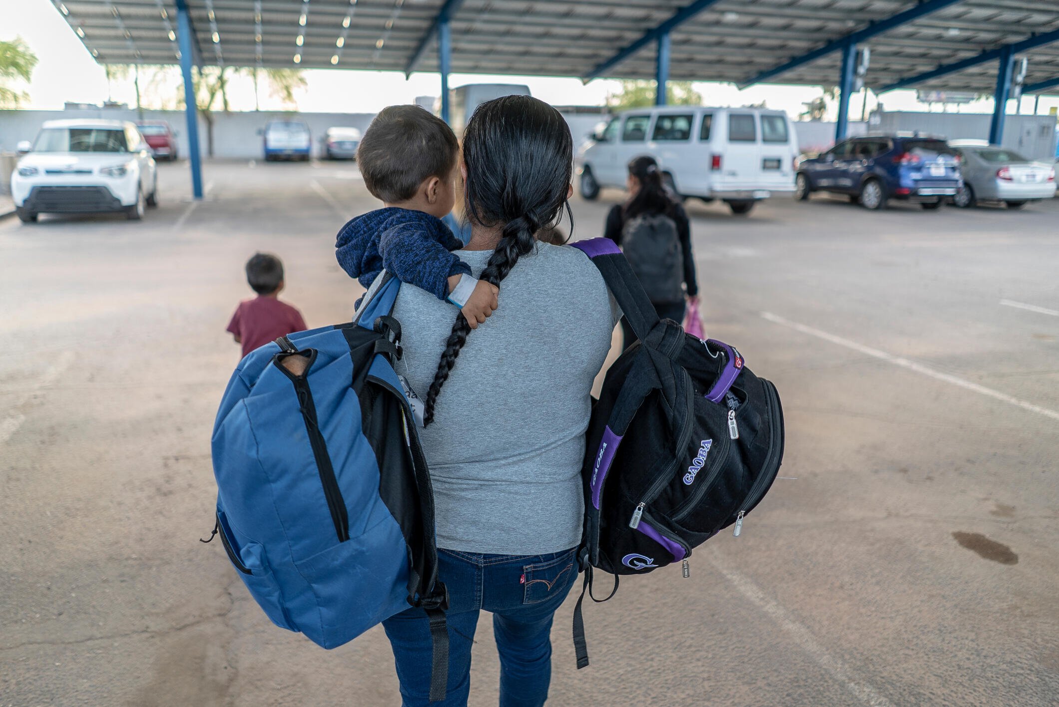 A Central American mother holds her child and two backpacks after arriving in Phoenix, Arizona