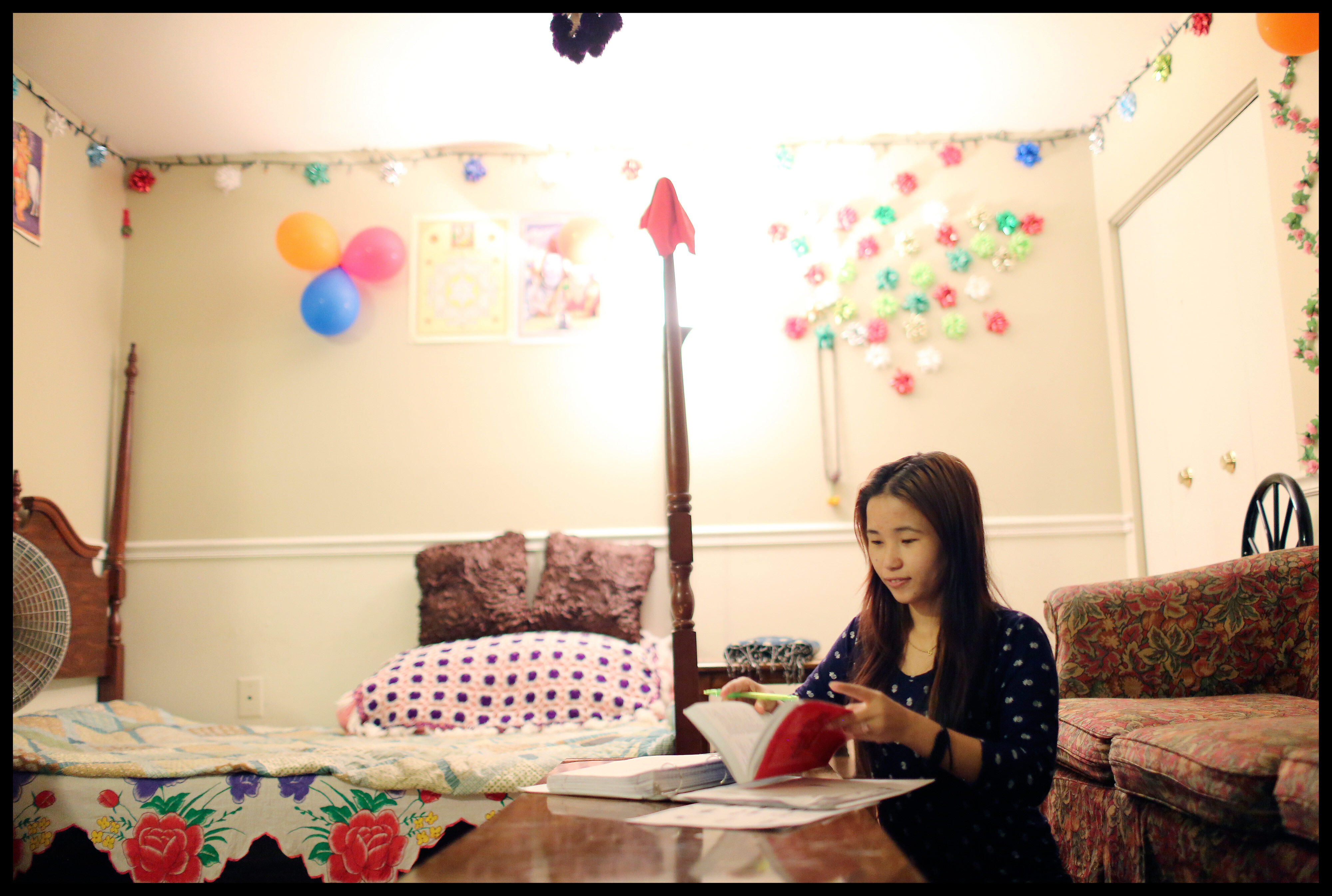 Teenage girl sits in her bedroom while doing schoolwork.