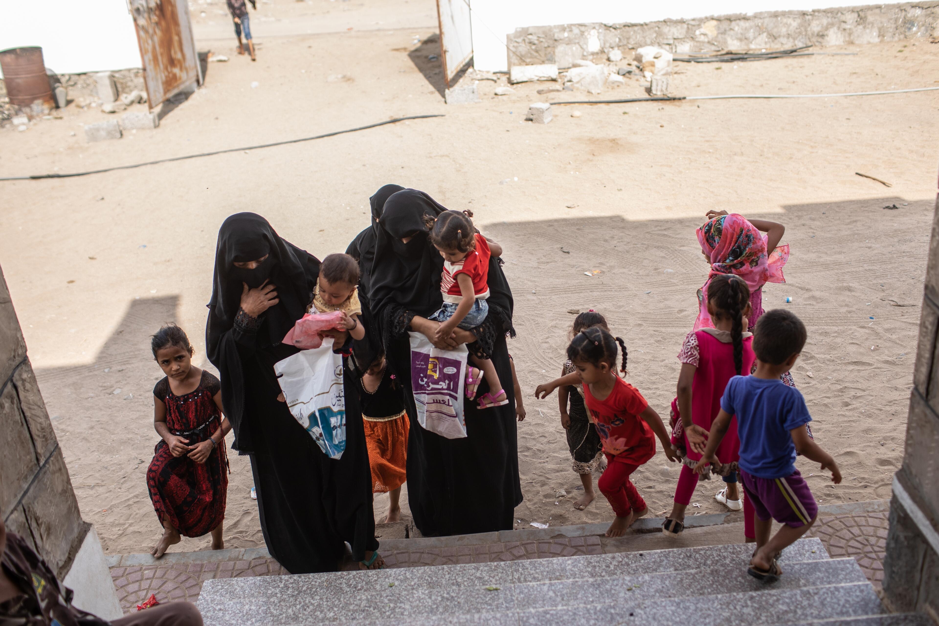 A group of mothers and children arrive at the steps of an International Rescue Committee center near Aden, Yemen