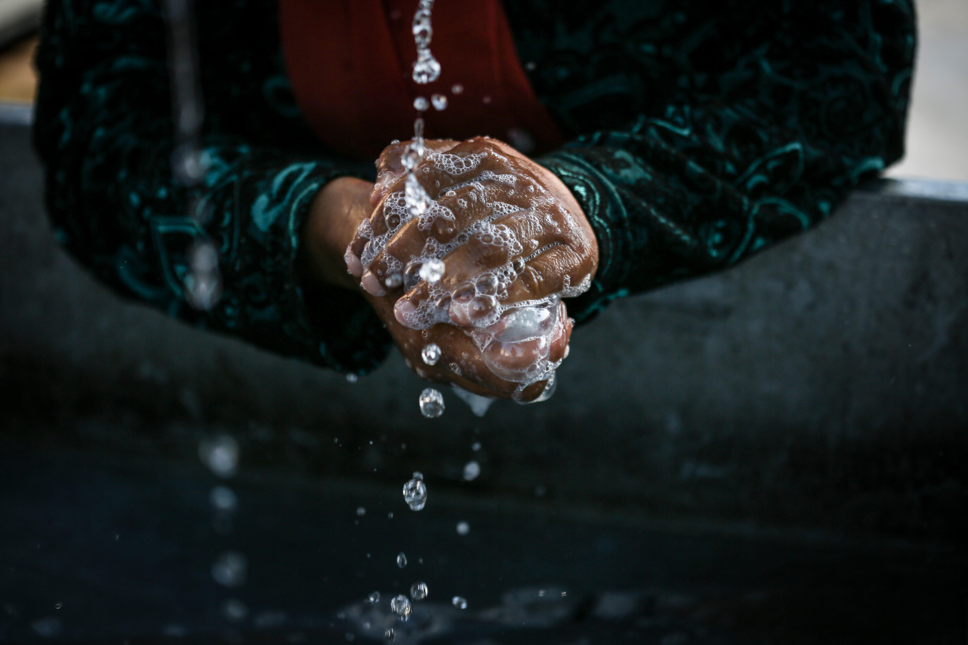 A woman cleans her hands at the Alexandria refugee camp in northern Greece, July 14, 2016.