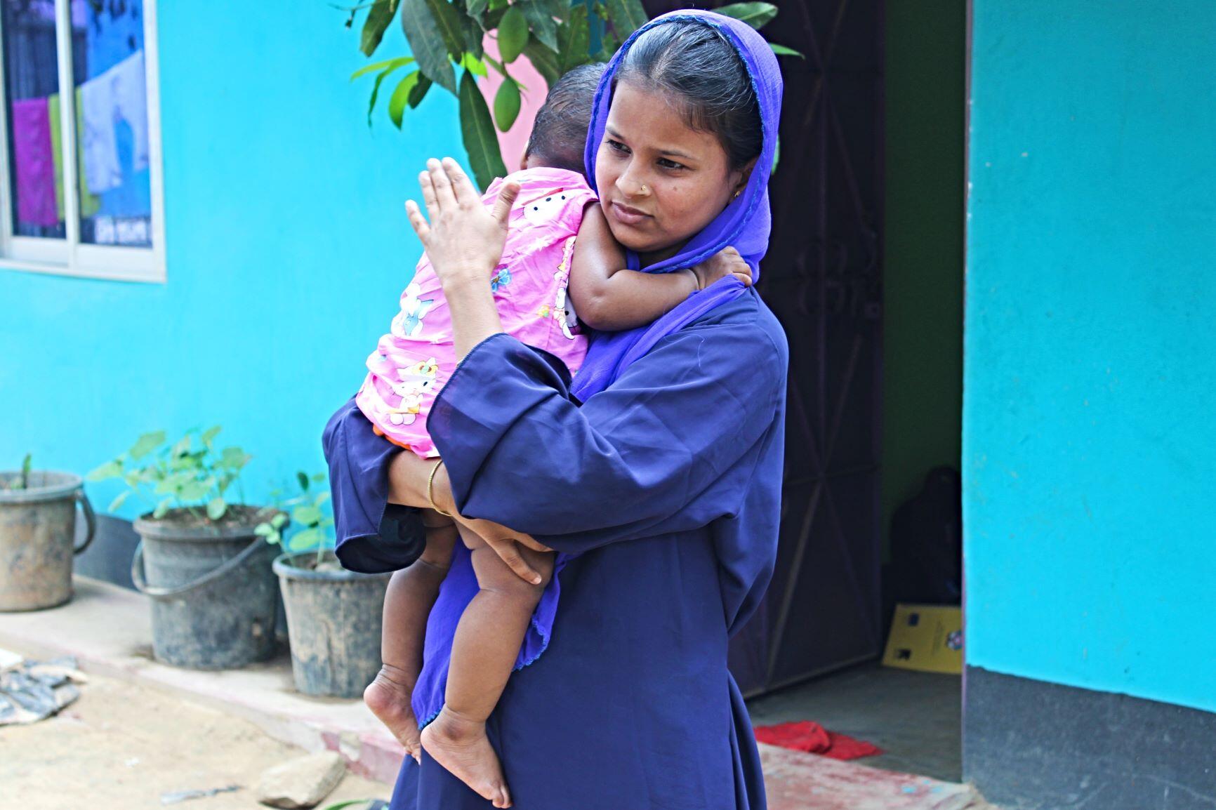 Lovely Akter holds her nine-month-old daugher