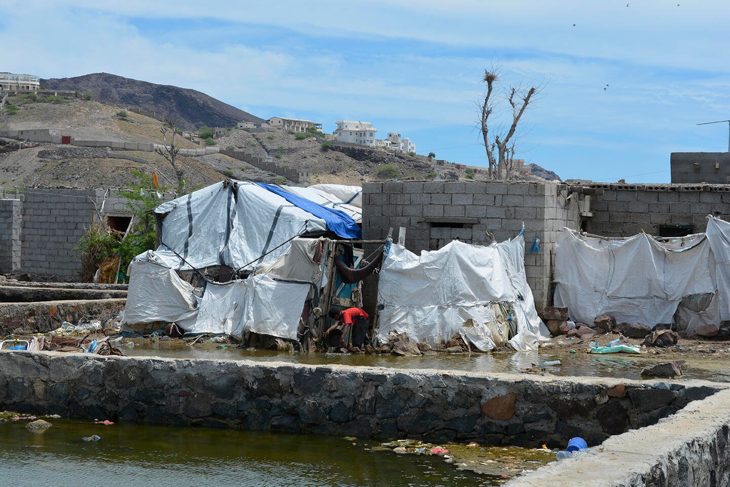 A displaced child bails water from a flooded tent near Aden, Yemen