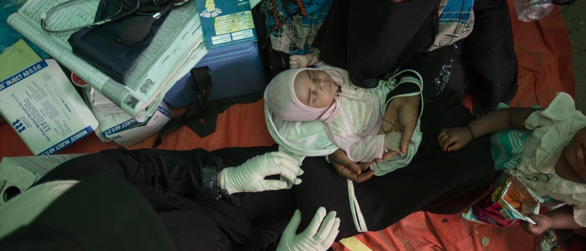 Bodo sits in a tent holding her baby, who she named Enqath or "Rescue" after the International Rescue Committee. 