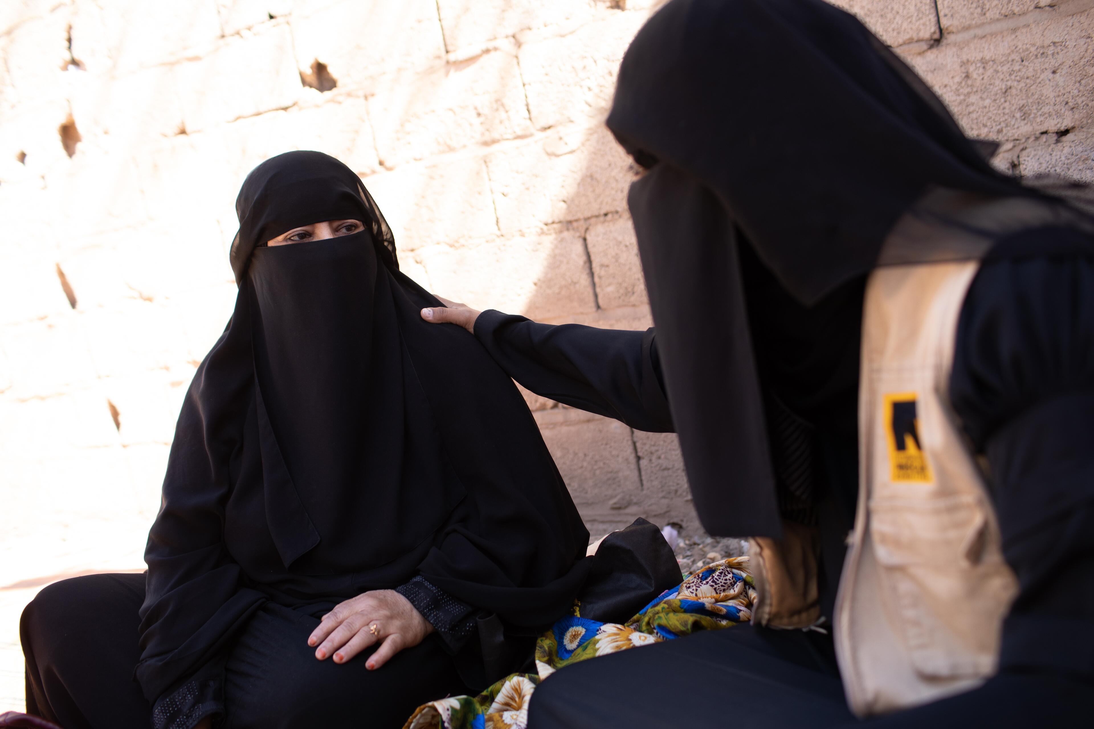 An IRC womens protection and empowerment staff member places her hand on a womans shoulder as they speak in Yemen.