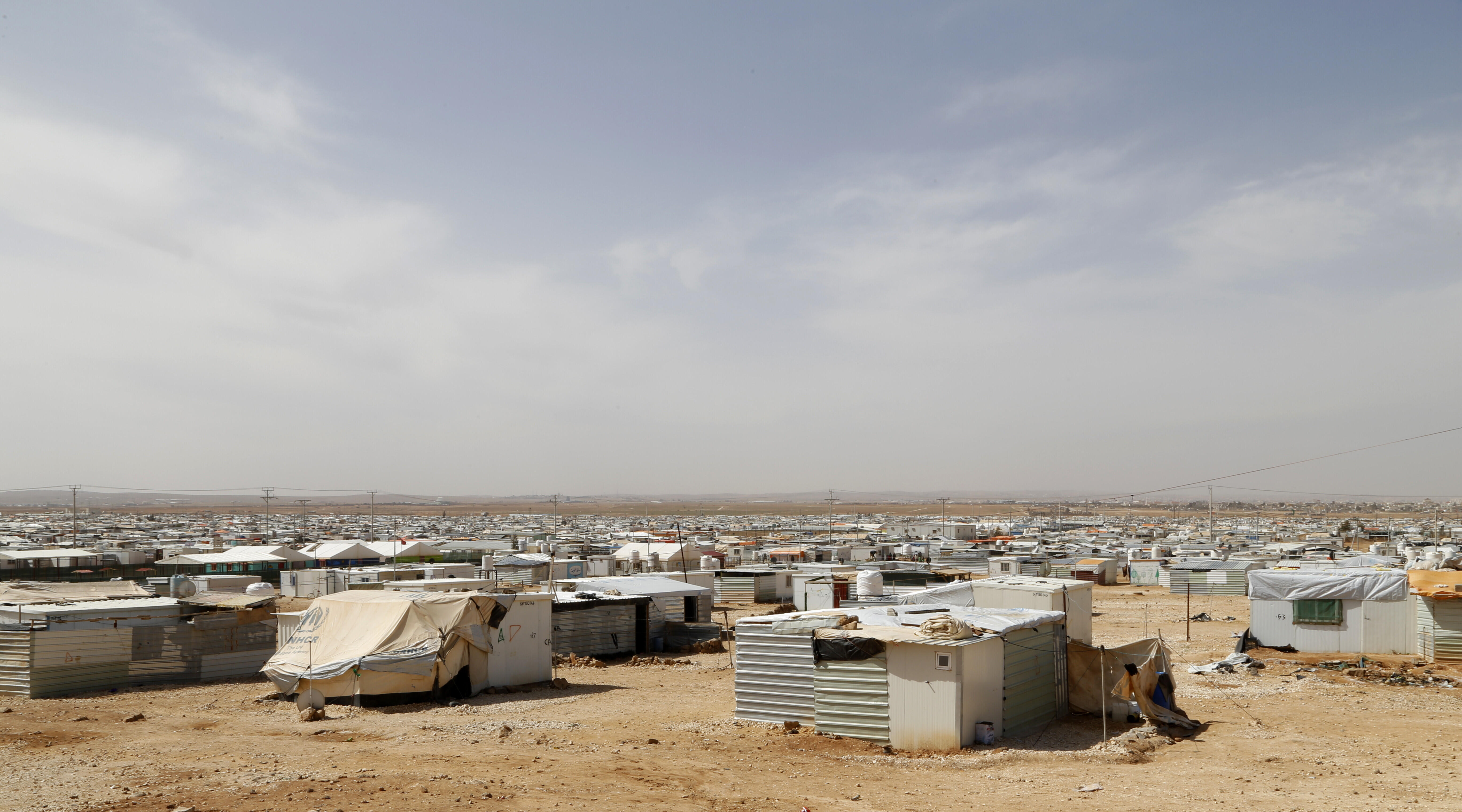 Zaatari refugee camp. The photo consists of many small tin houses on a flat desert landscape. 