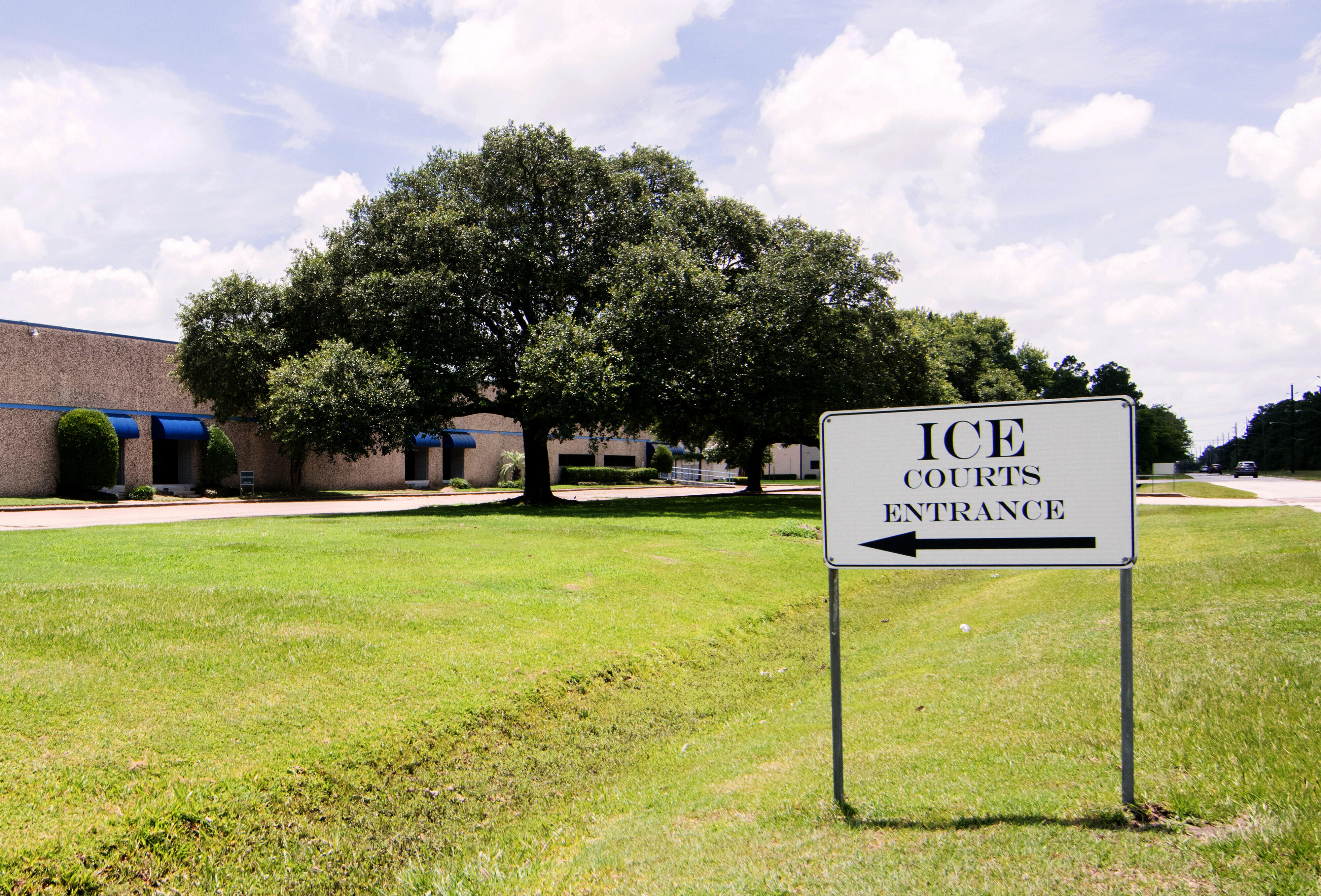 A lawn with a black and white sign that says "ICE Courts Entrance"