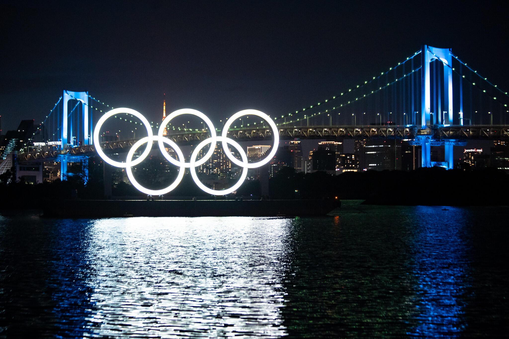 Monument of Olympic Rings at night, set on a barge in Tokyo with a bridge behind it for Tokyo 2020