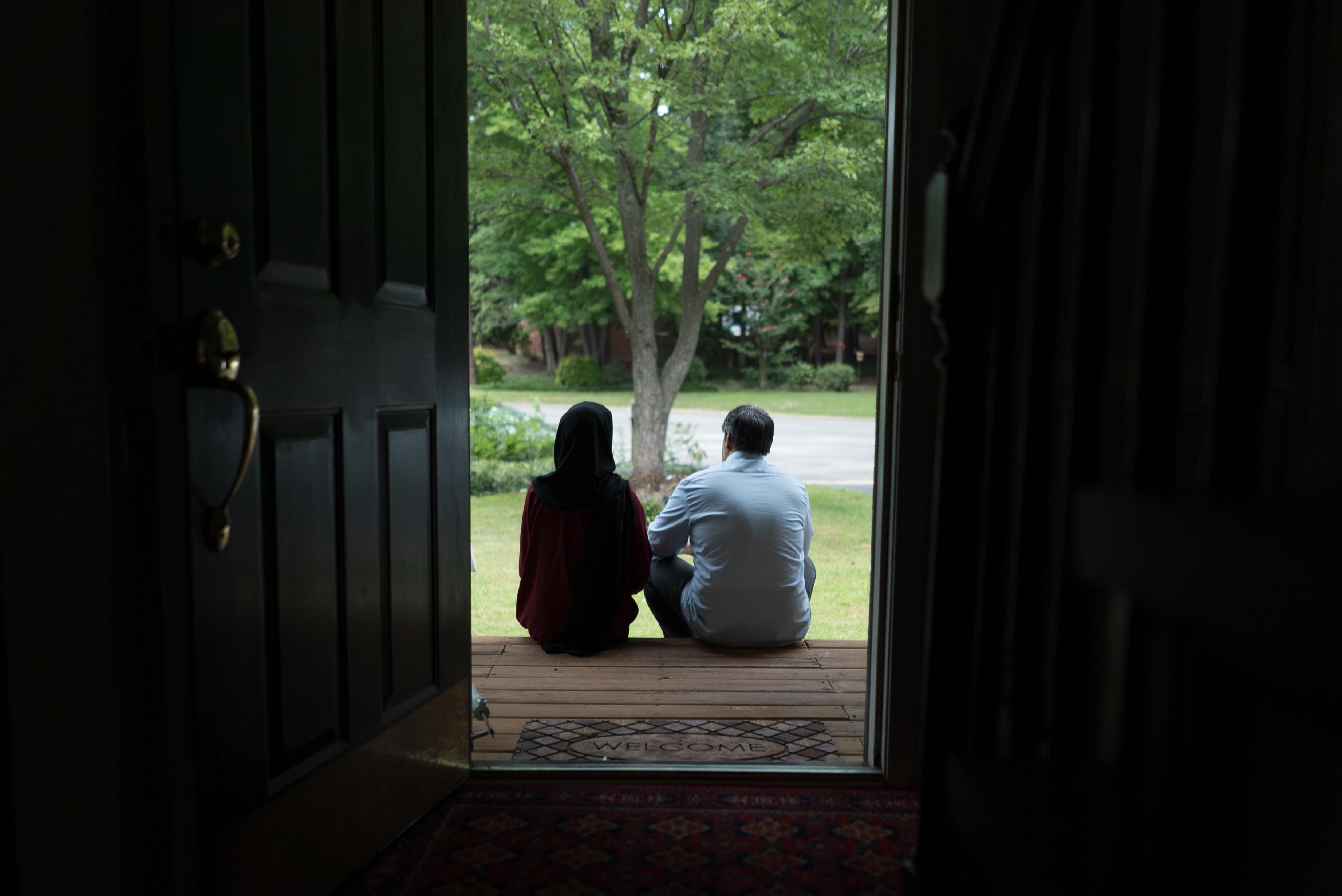 Afghan refugees Fatima, 19, and her father Abdul, 52, sit on the wooden front steps of their Virginia home looking out at the garden