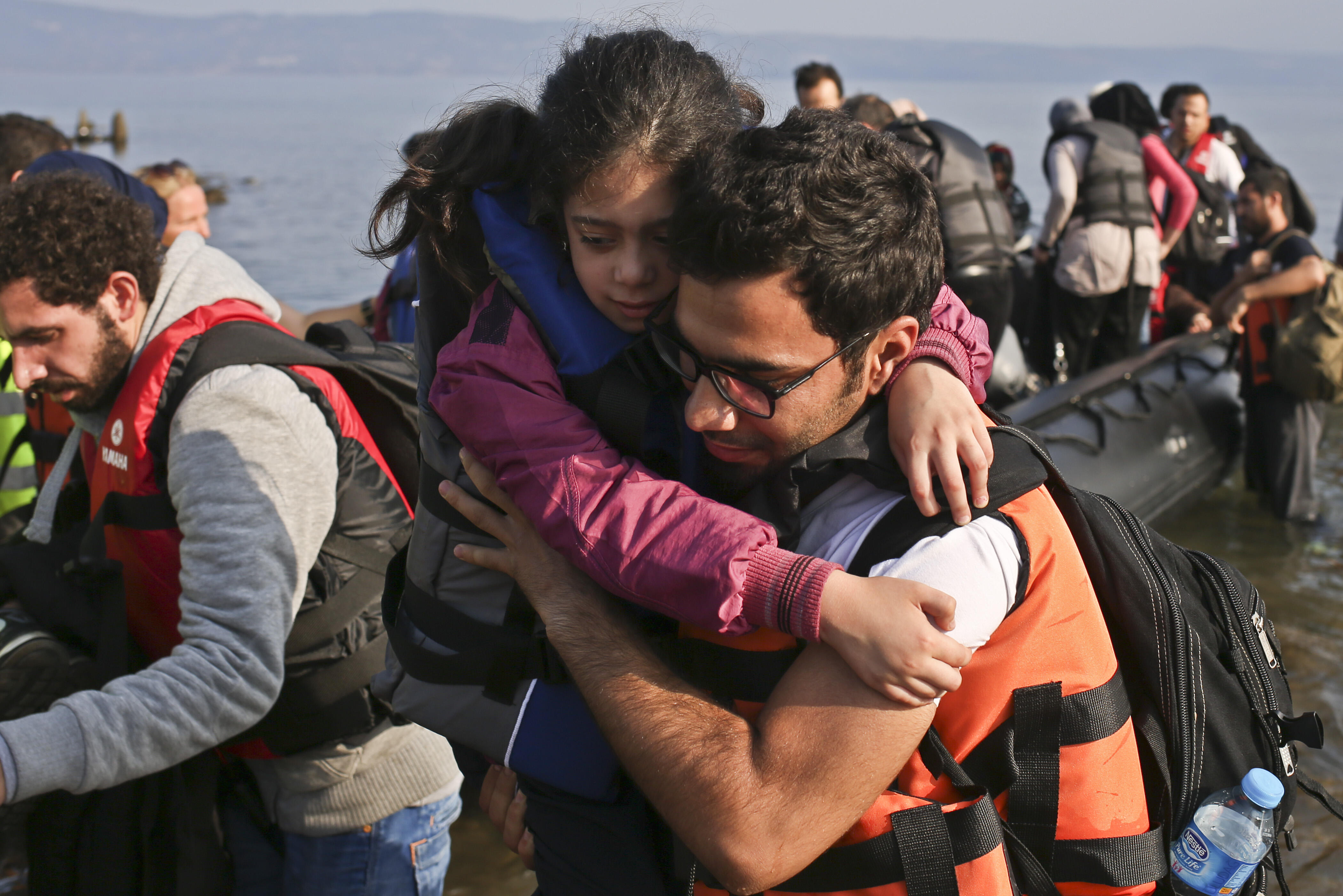 A Syrian man carries a little girl onto a Greek beach after arriving in a small boat from Turkey.