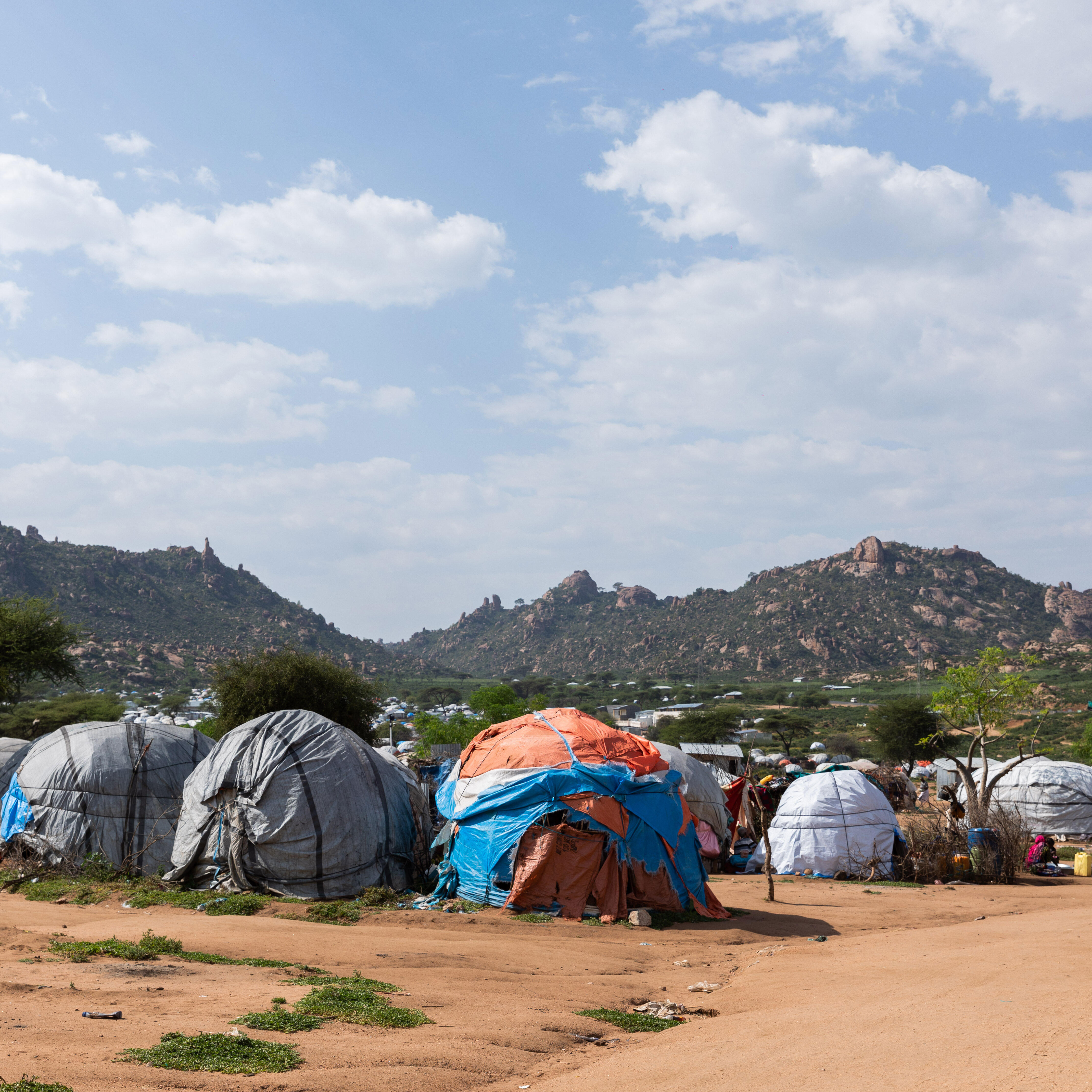 A landscape photo of tents with mountains in the distance. 