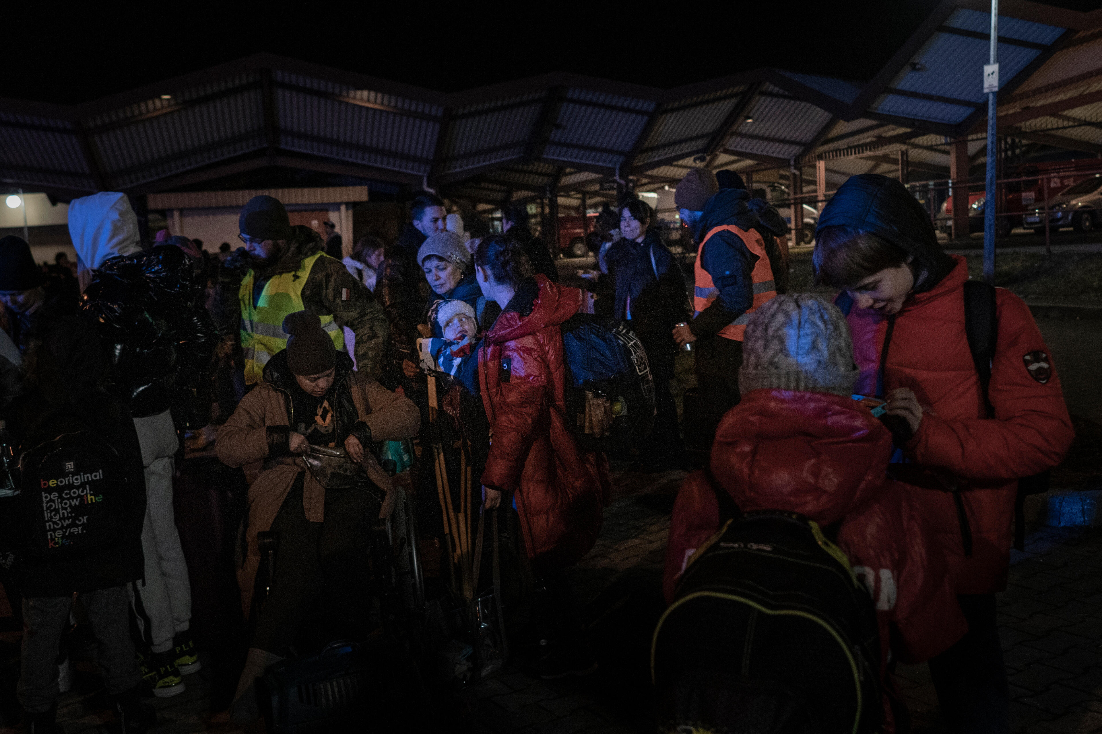 A group of refugees from Ukraine wait at a Polish train station at night after crossing the Ukraine-Poland border