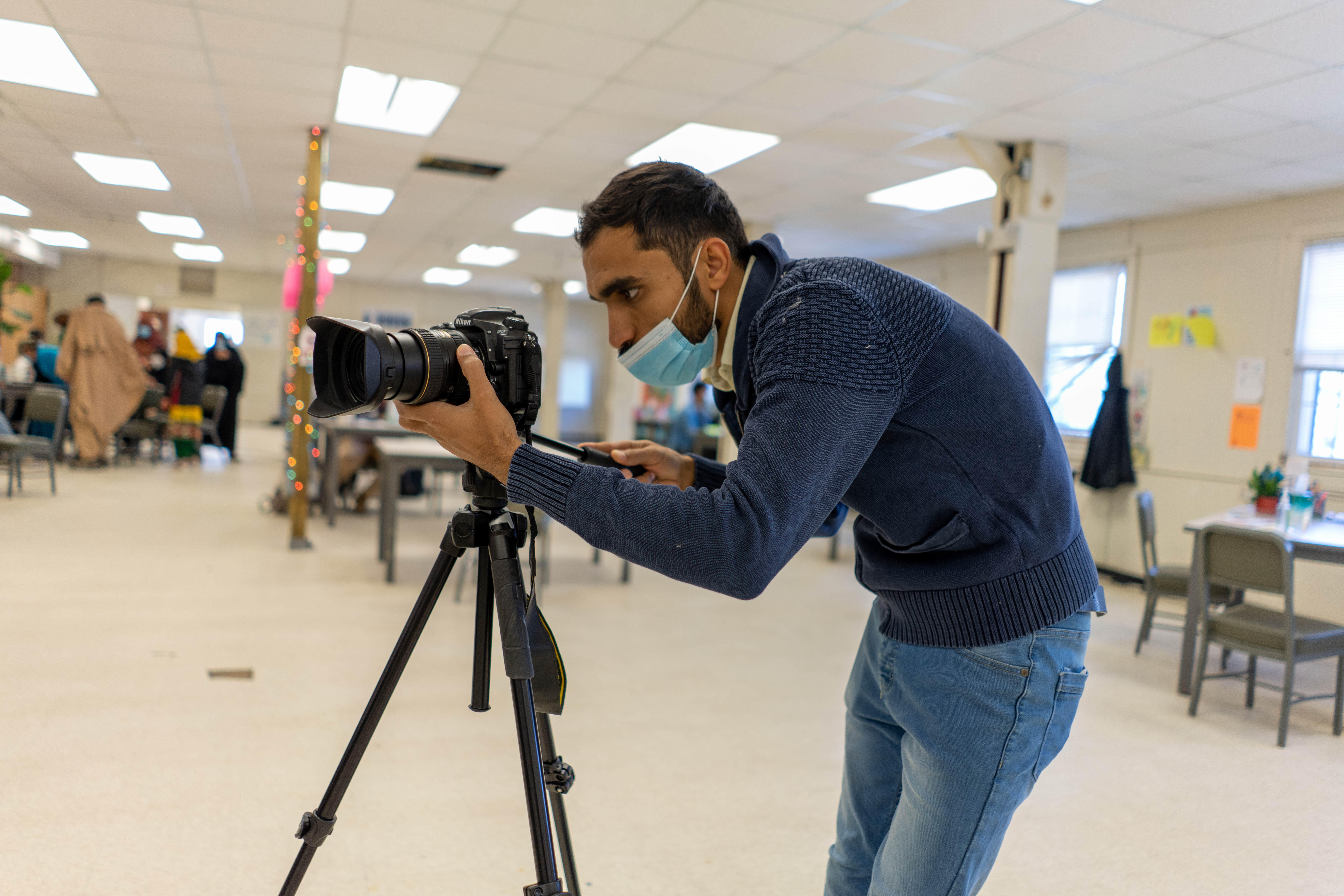 Photojournalist Mohammad Anwar Danishyar adjusts the lense of his camera while filming Afghan refugees and the IRCs work in a U.S. government safe haven