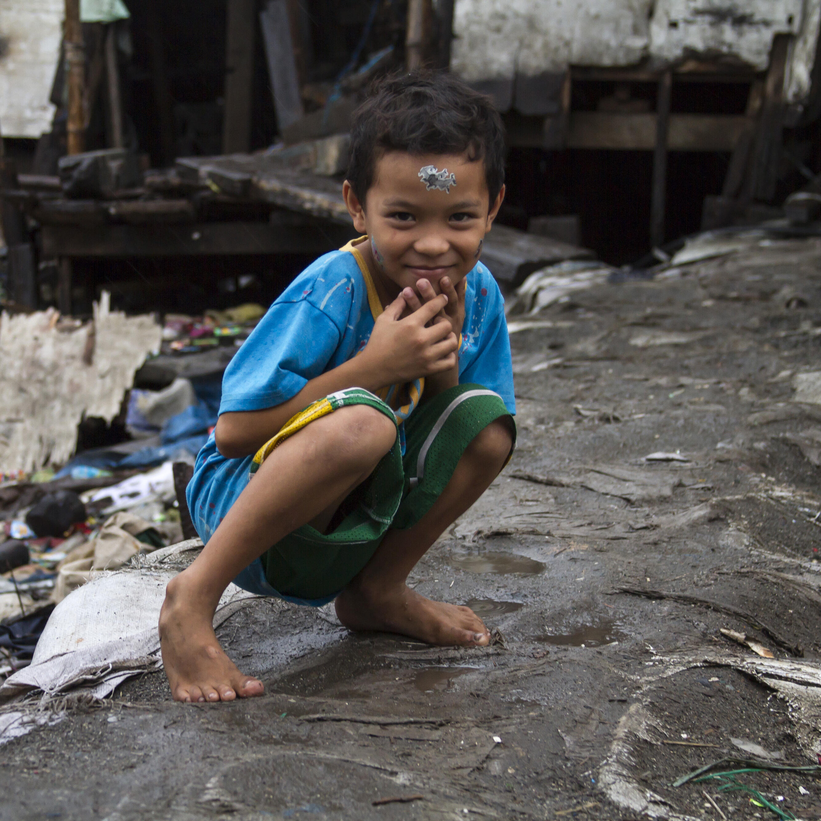 A child crouching in front of a building.