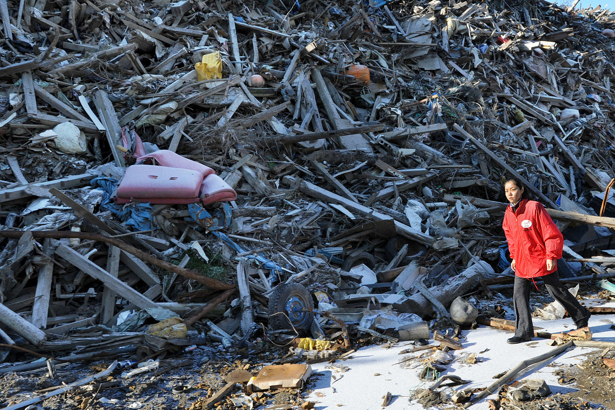 A Japanese aid worker walks through the debris of ruined buildings