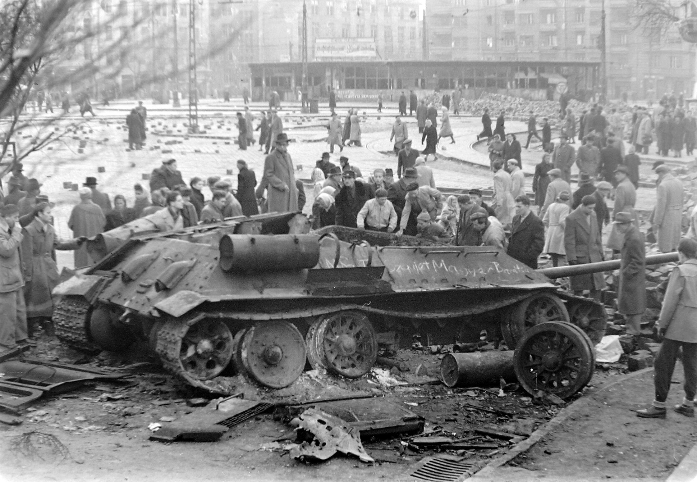 A destroyed Soviet T-34-85 in Budapest is surrounded by civilians