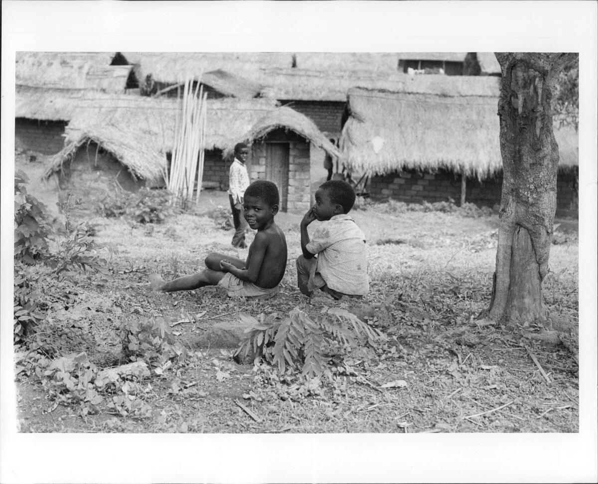 Angolan refugee children sit on the ground outside a row of houses in Zaire.