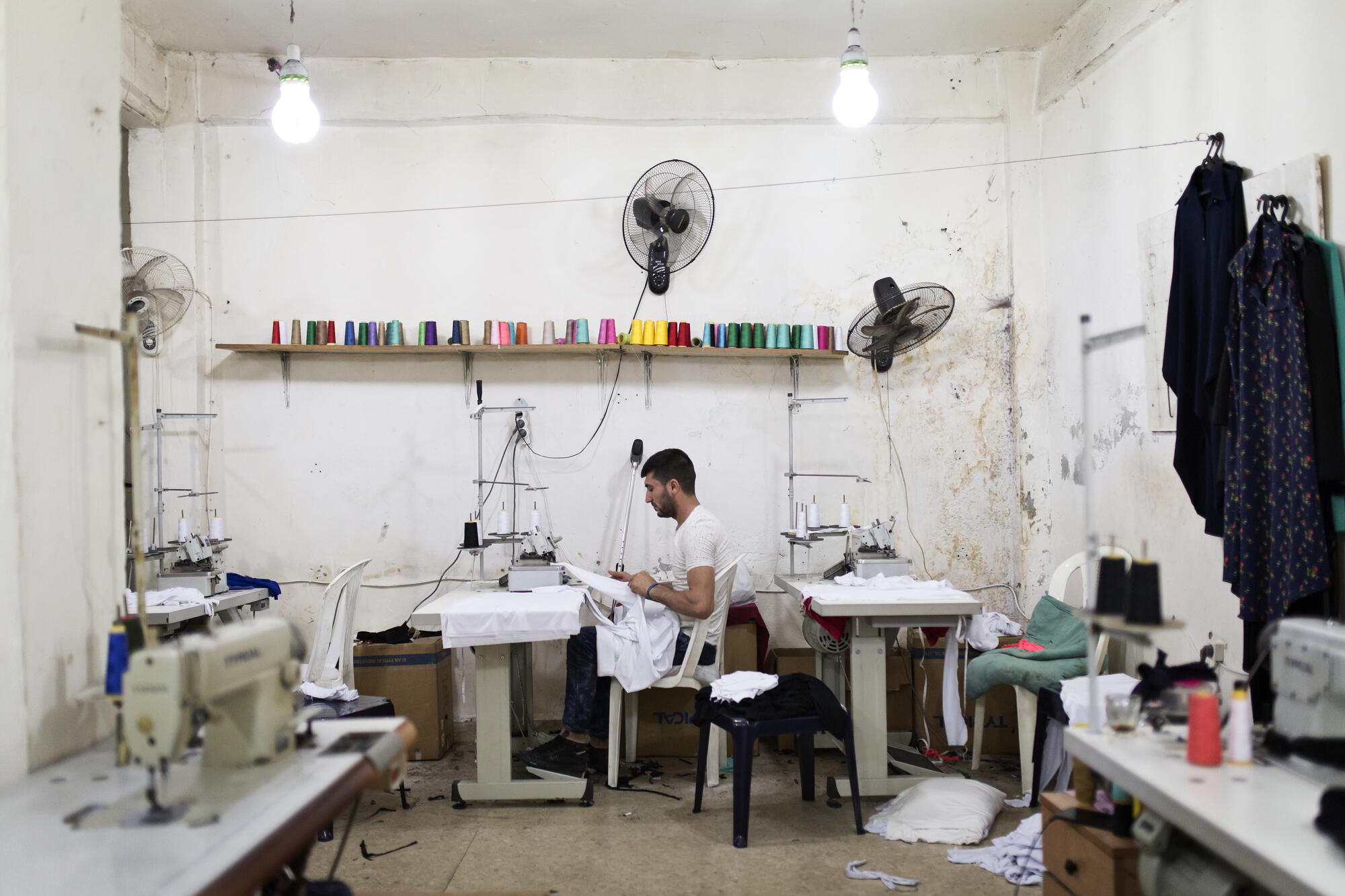 Mohamed Saleh Ismail works at a sewing machine in a tailoring workshop where he is an apprentice.
