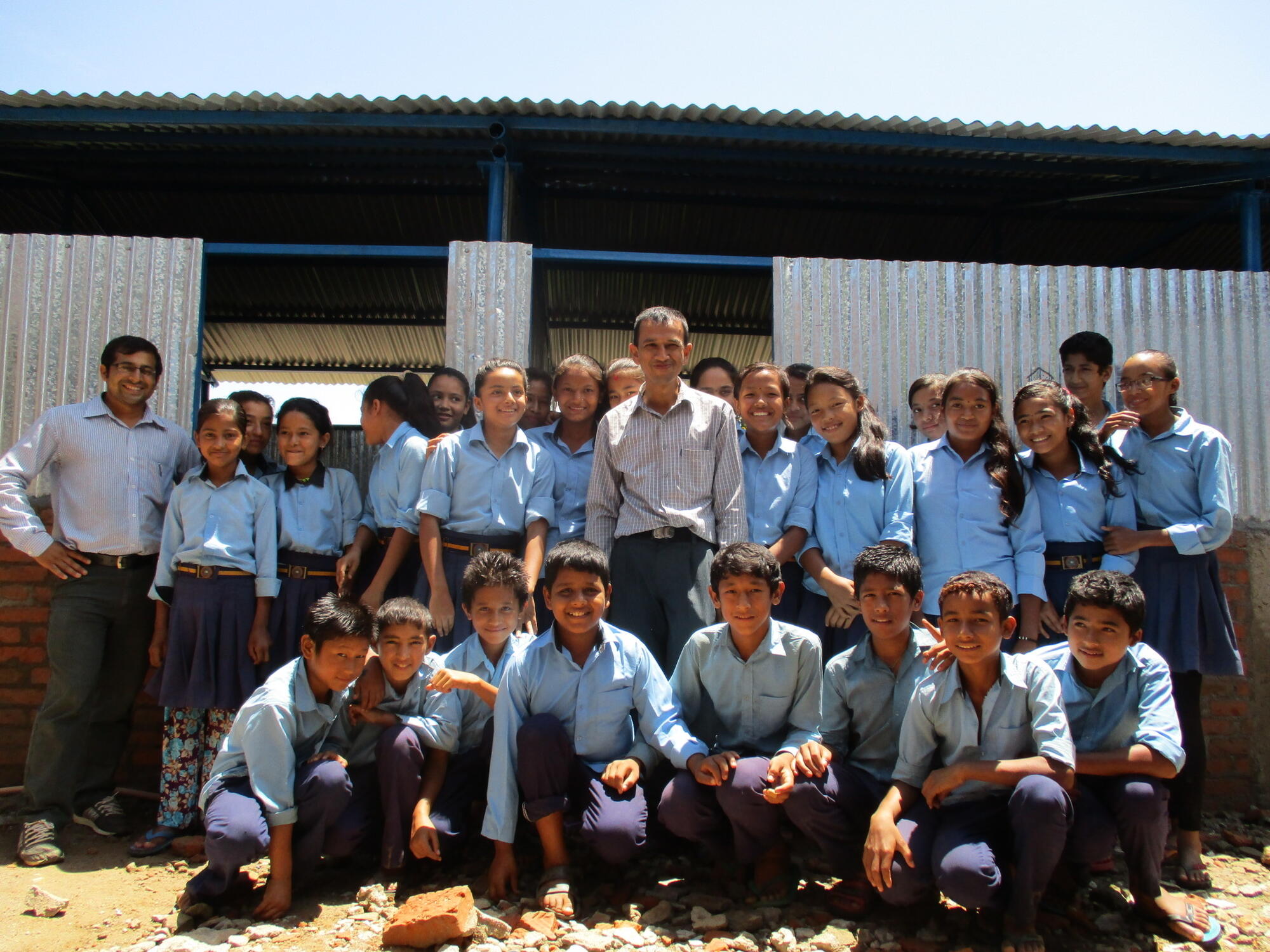 Secondary school principal Roshan Dhakal and some of his students outside a temporary learning centre.