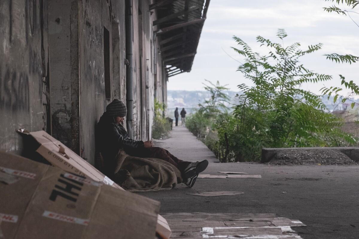 A young Afghan refugee sits huddled outside an abandoned warehouse in Serbia.