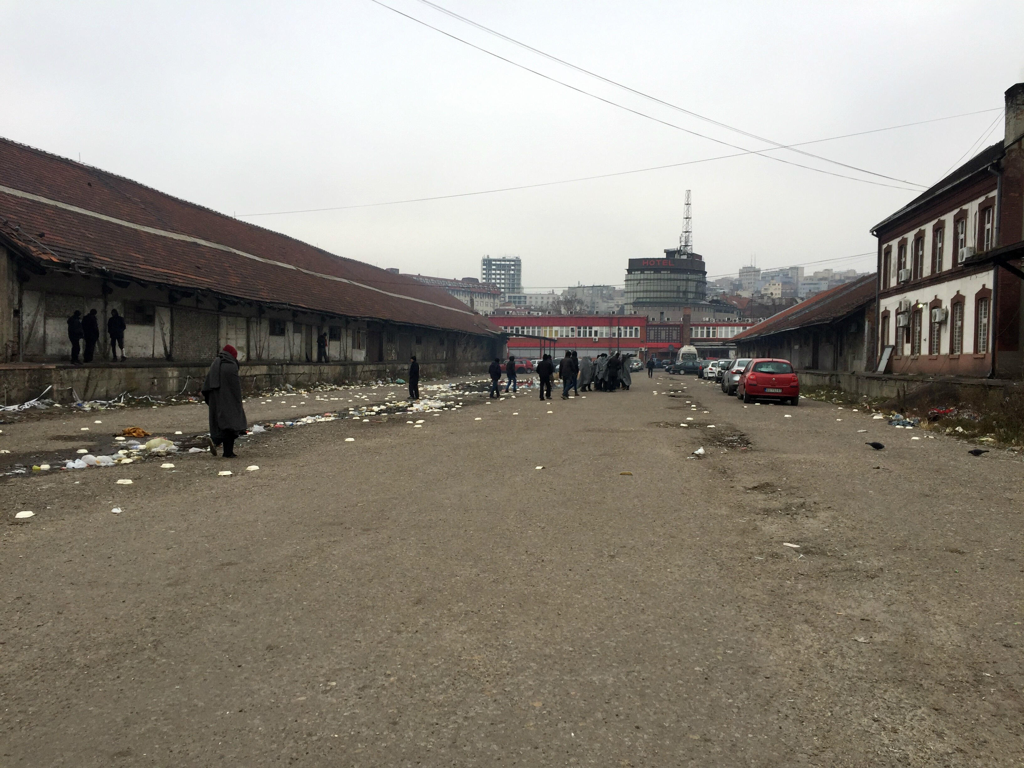 Young refugees wrapped in blankets for warmth gather on the street outside an abandoned warehouse in a Belgrade industrial strip that has become a makeshift shelter.