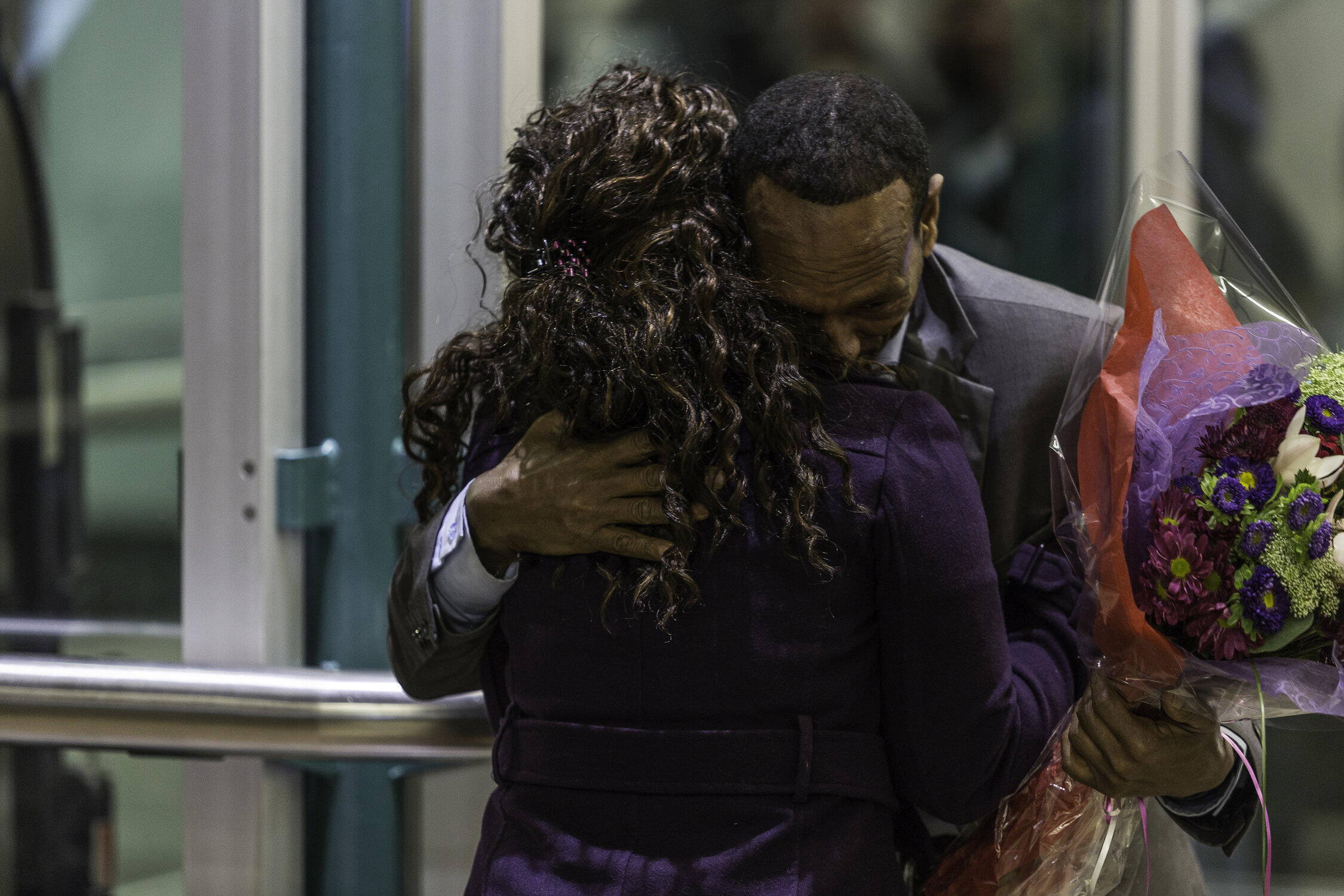 A Somali father holiding a bouquet of flowers hugs his daughter just after they are reunited in Seattle's SeaTac airport