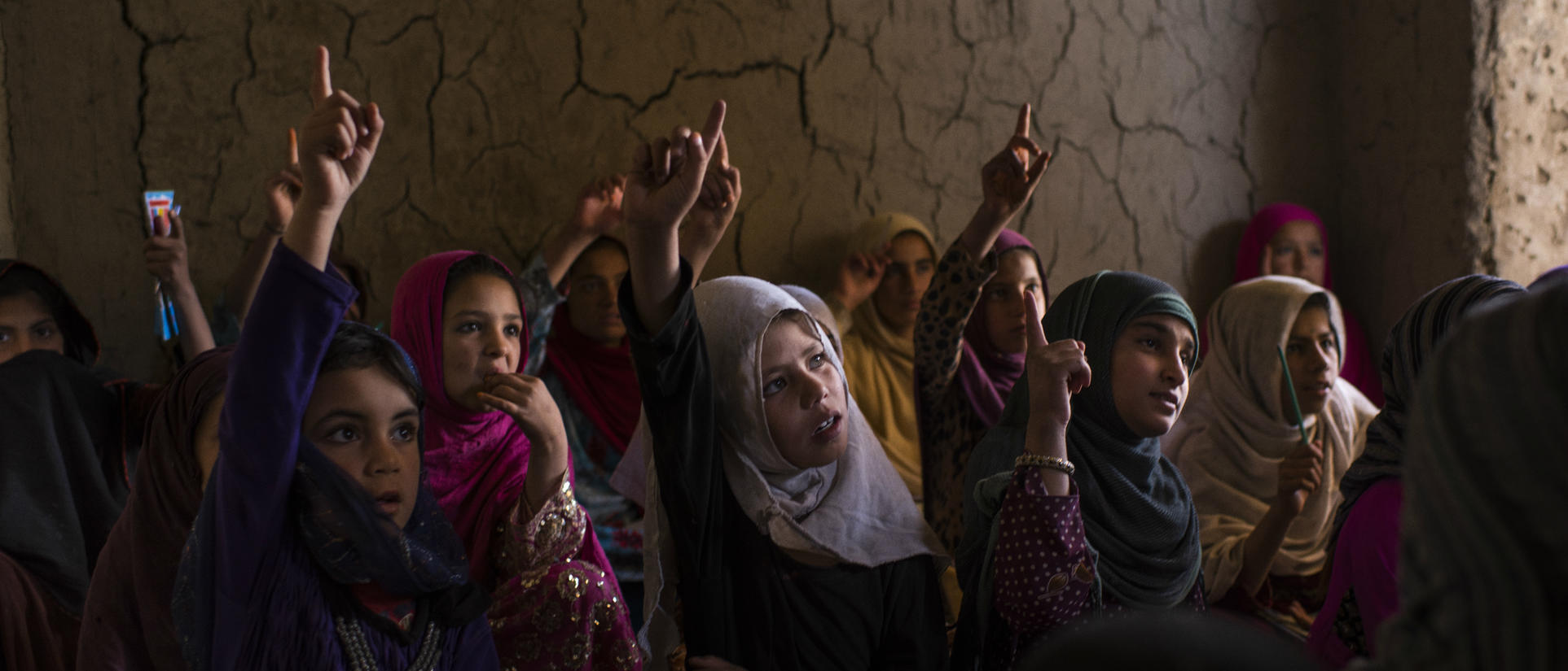 A group of school girls raise their hands 