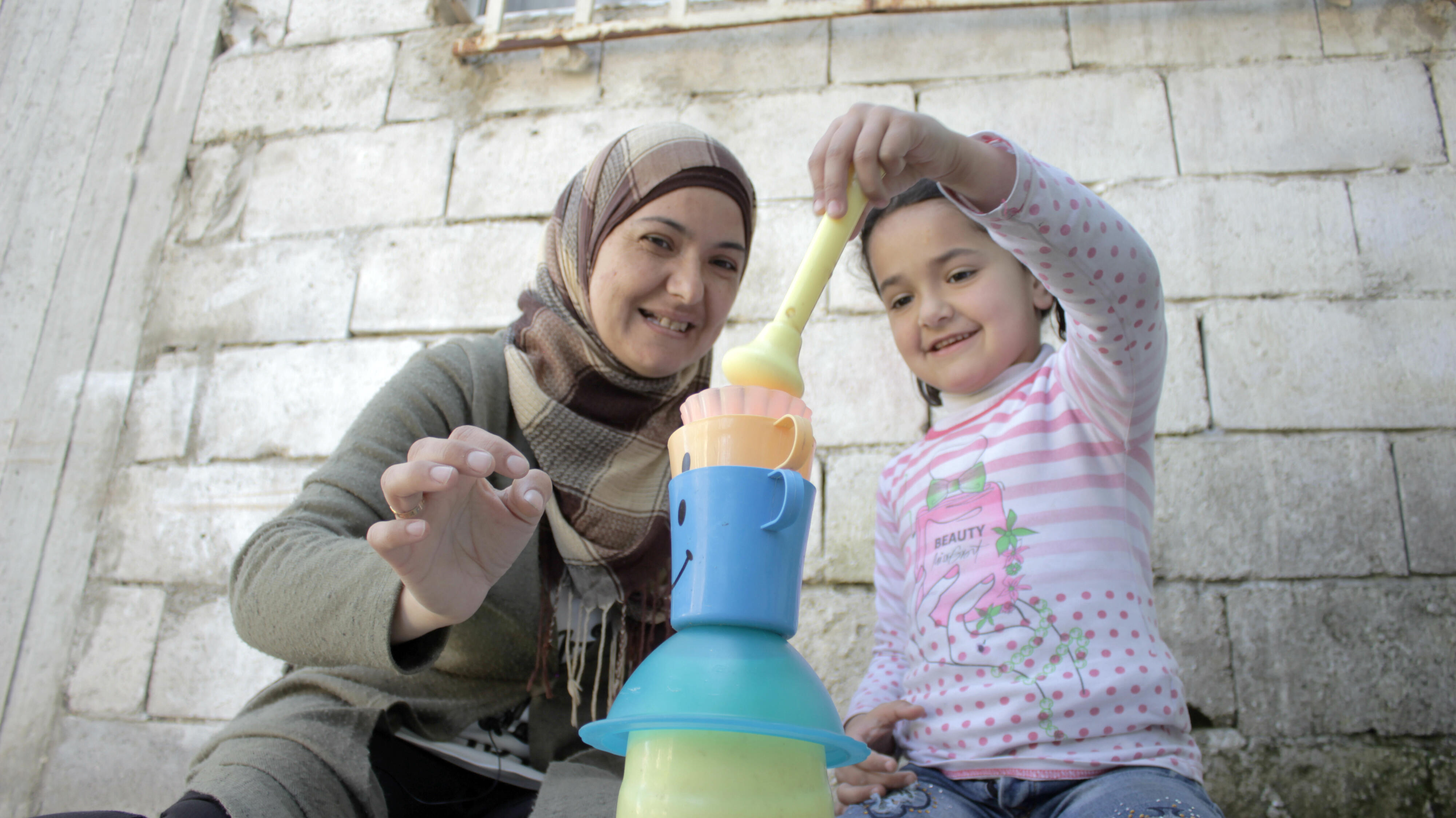 Ahlam and Sadal stack plastic cups as part of a Vroom activity