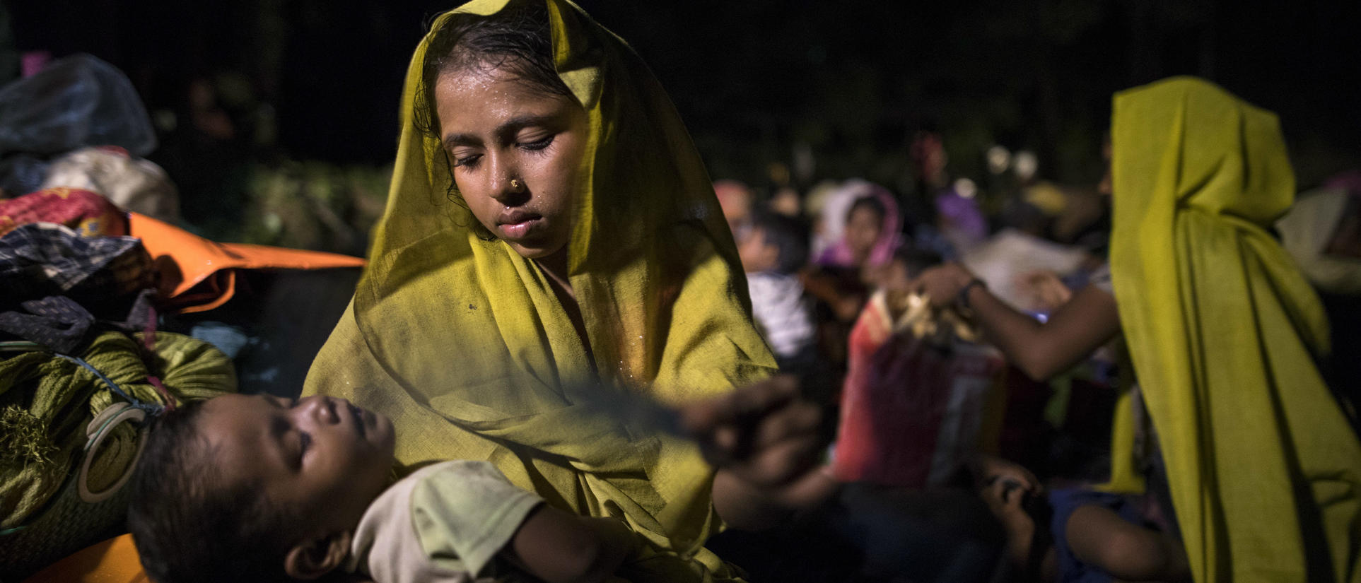 A Rohingya Muslim mother carries her sleeping baby