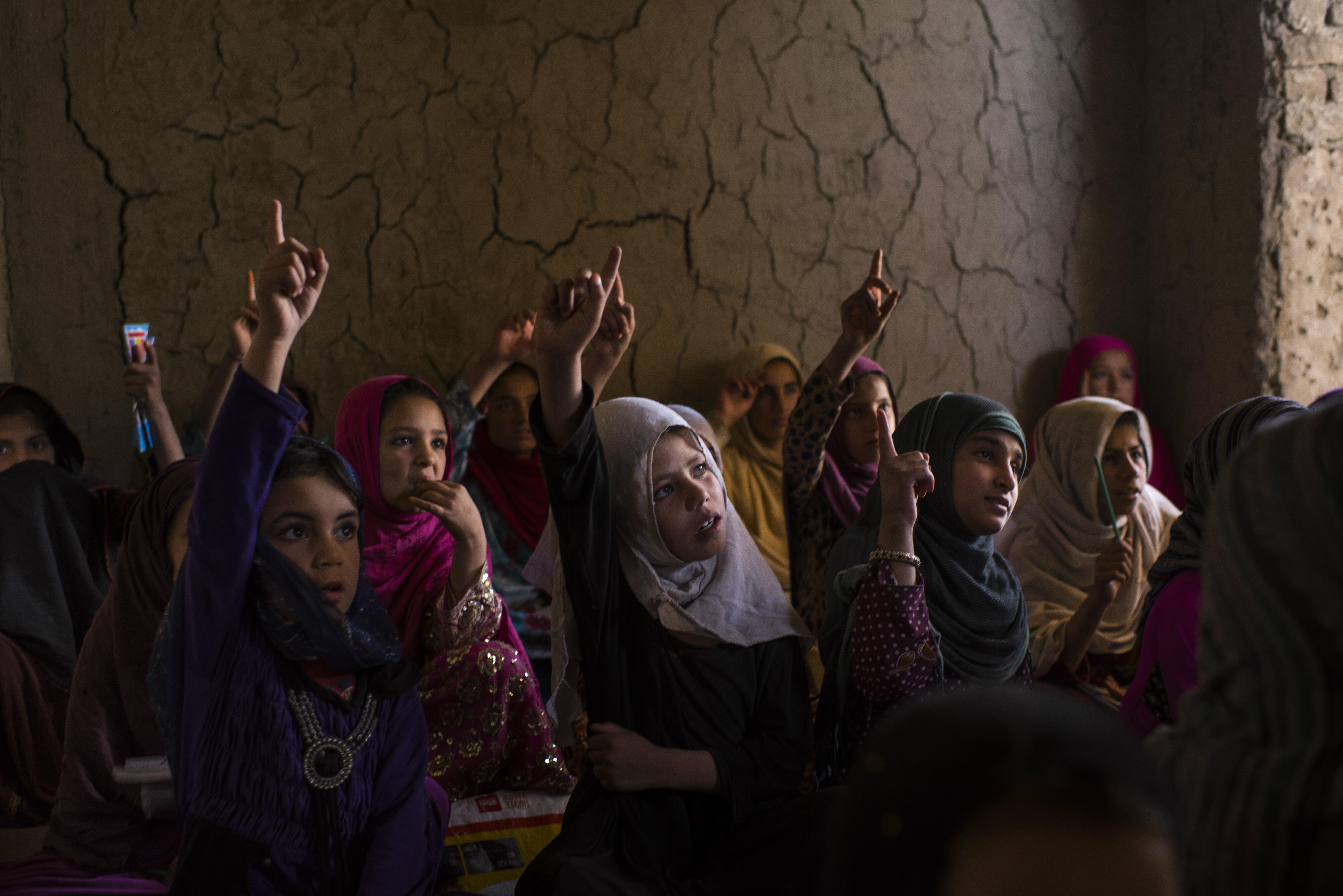 Afghan girls raise their hands in class