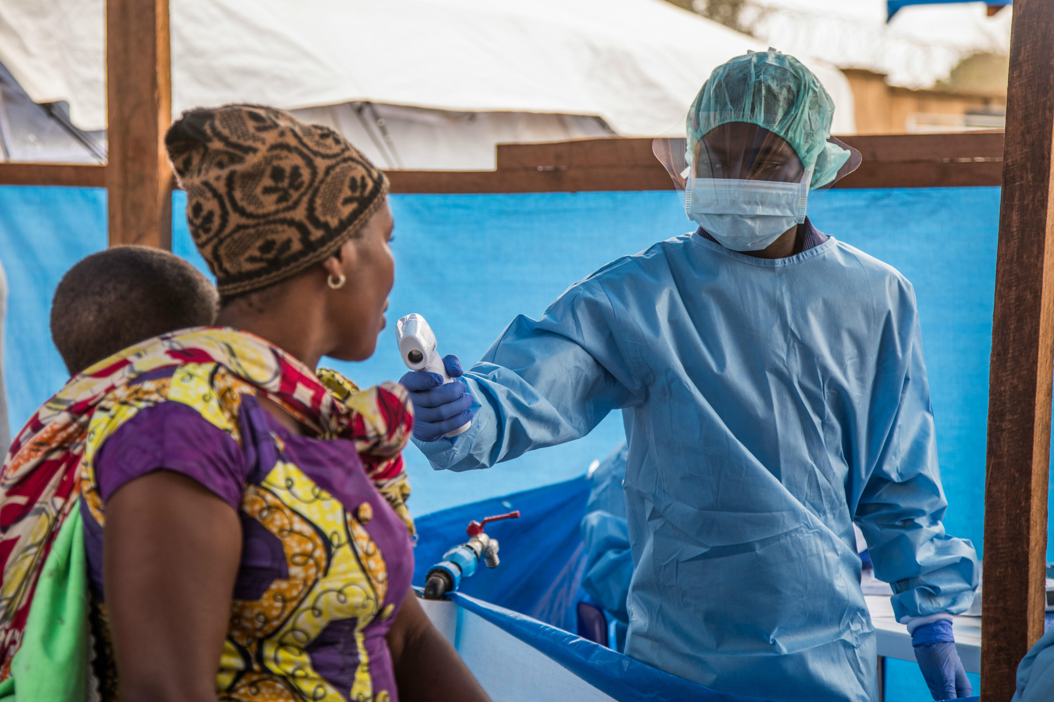 A health workers uses a scanner to screen a woman and baby for signs of Ebola