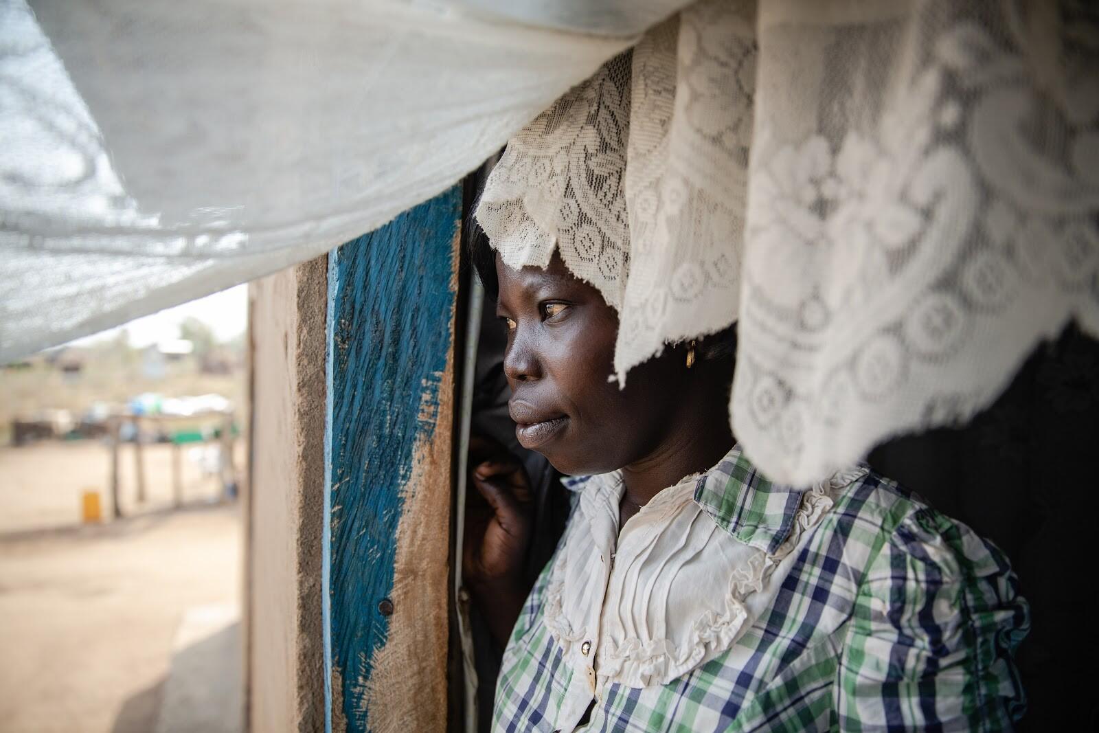 Foni Grace, an women’s rights activist, who is supported by the IRC looks out of her home in Bidi Bidi Camp in Uganda. IRC staff are now supporting her remotely via the phone.