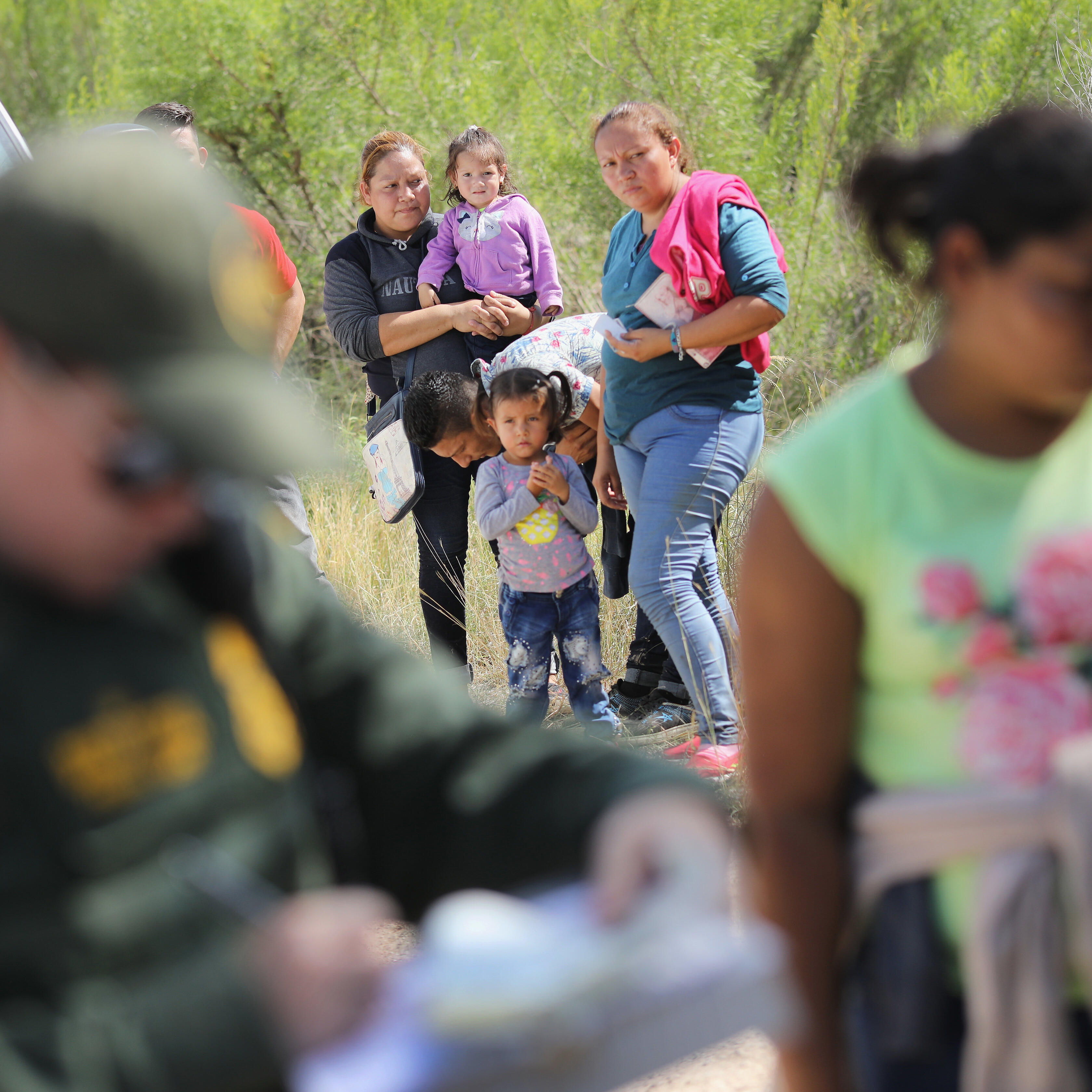 Central American asylum seekers wait as a U.S. Border Patrol agents take groups of them into custody on June 12, 2018 near McAllen, Texas. photo by John Moore/Getty Images