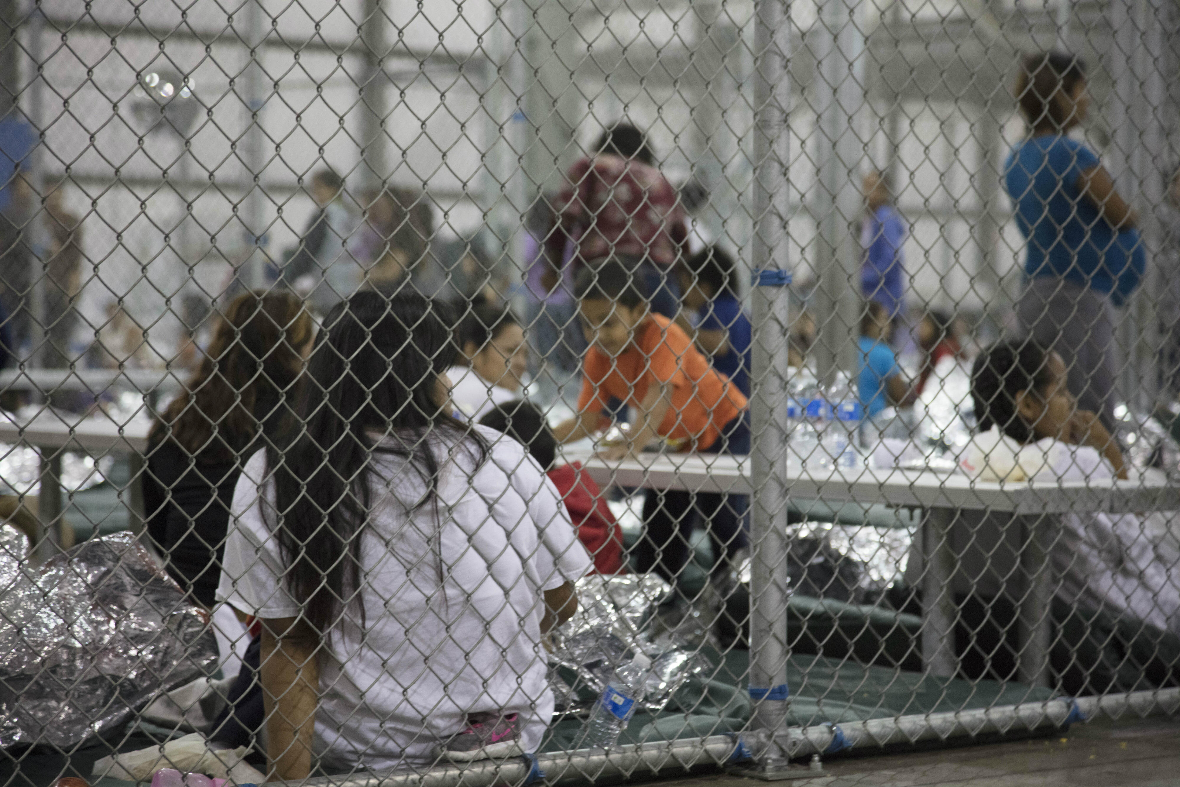 Families detained behind a chain-link fence inside a U.S. Border Patrol facility in Texas
