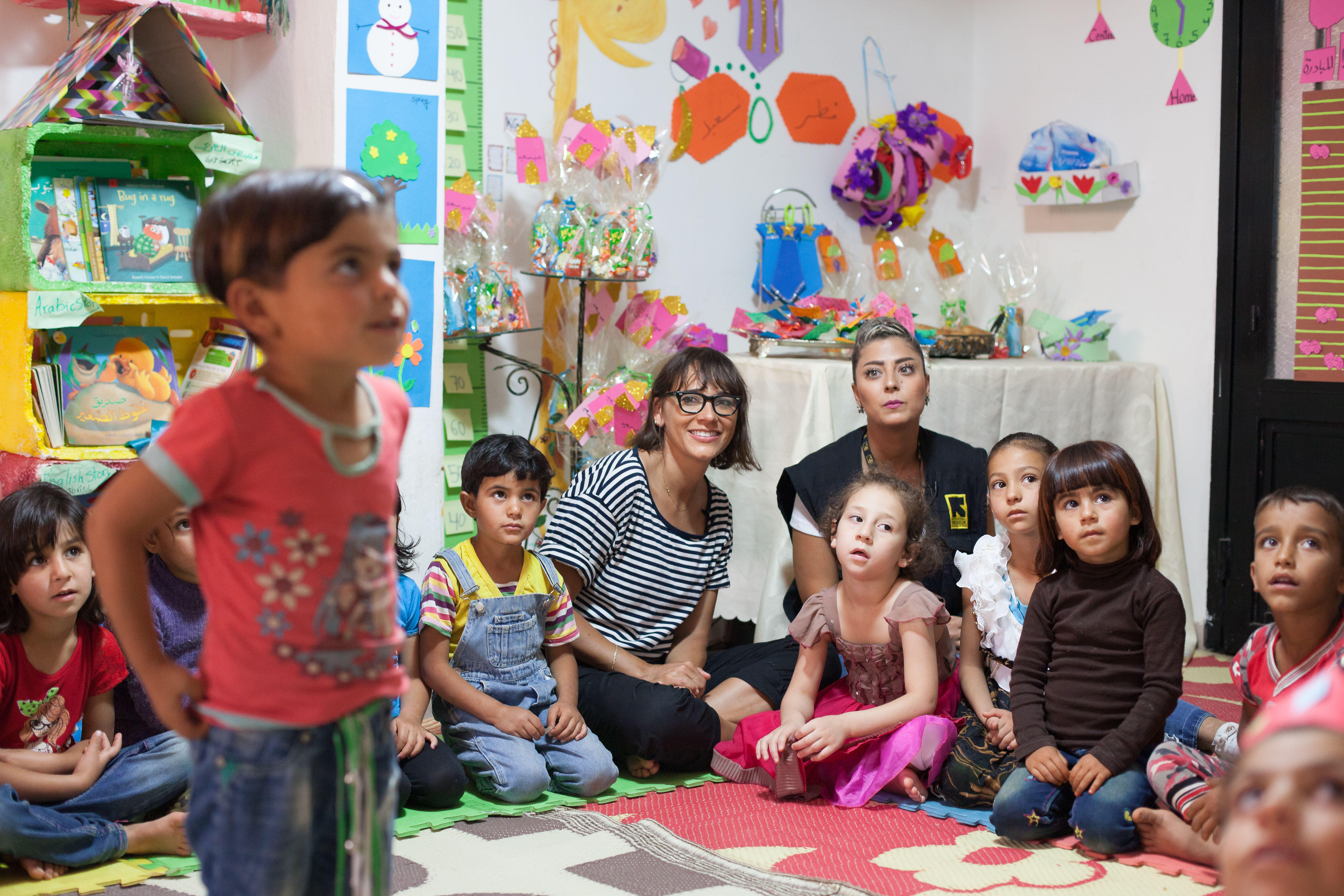 Rashida Jones sits with a small group of children at an IRC Safe Healing and Learning Space for young Syrian refugees in Lebanon.