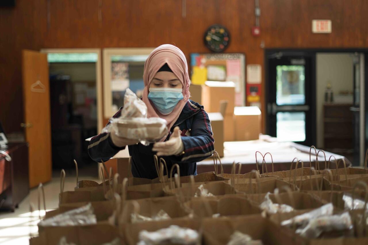 Refugee Rania Abou from Damascus, Syria distributes meals to people experiencing food insecurity in New Jersey, USA during the COVID-19 pandemic. 