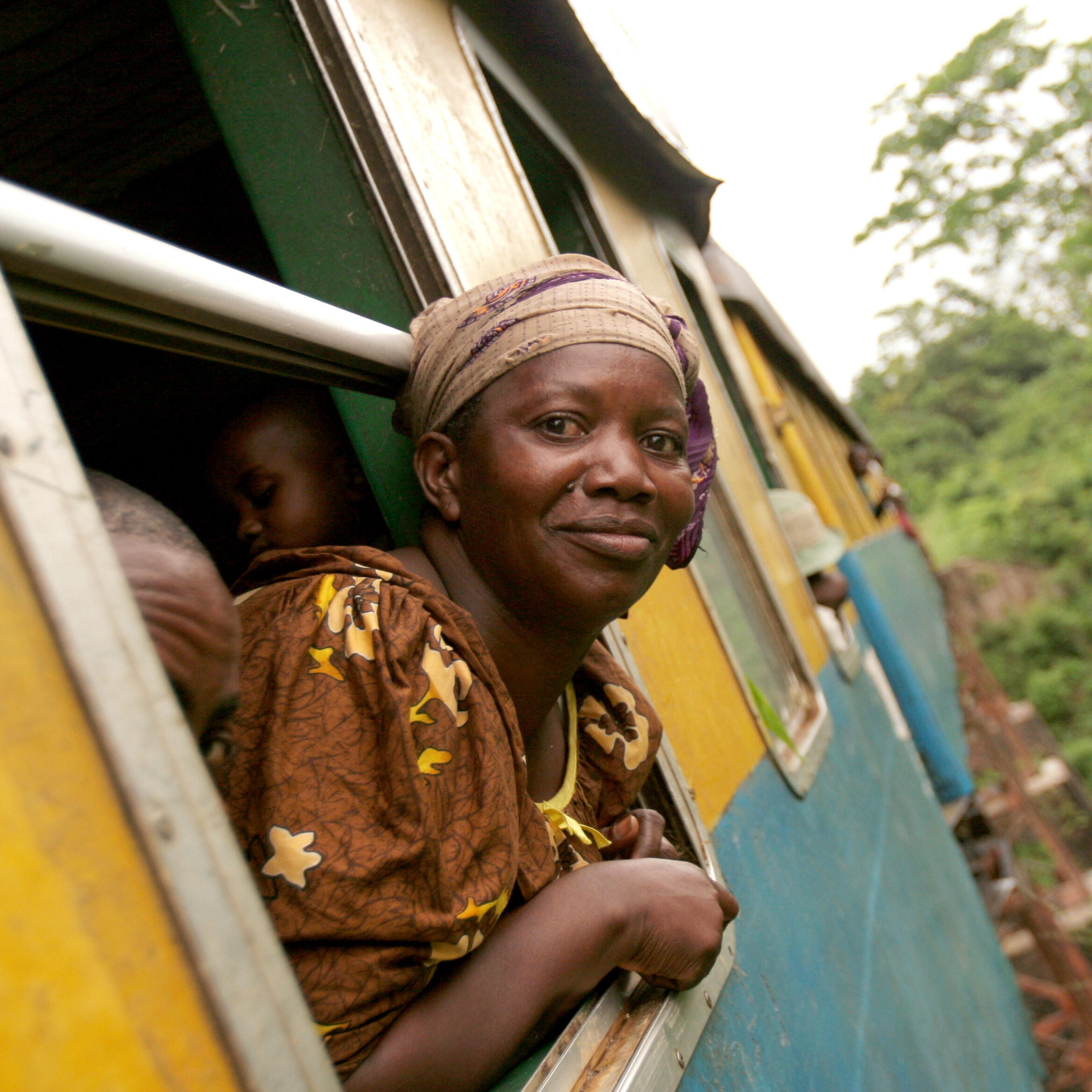 Congolese woman sticking head out of moving railroad car en route to market.