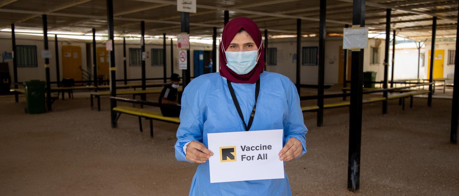 IRC senior health officer holding a sign saying "Vaccines for All"