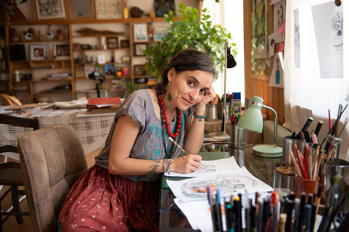 Artist Diala looks up at the camera from her desk where she is designing the IRC's WRD illustration.