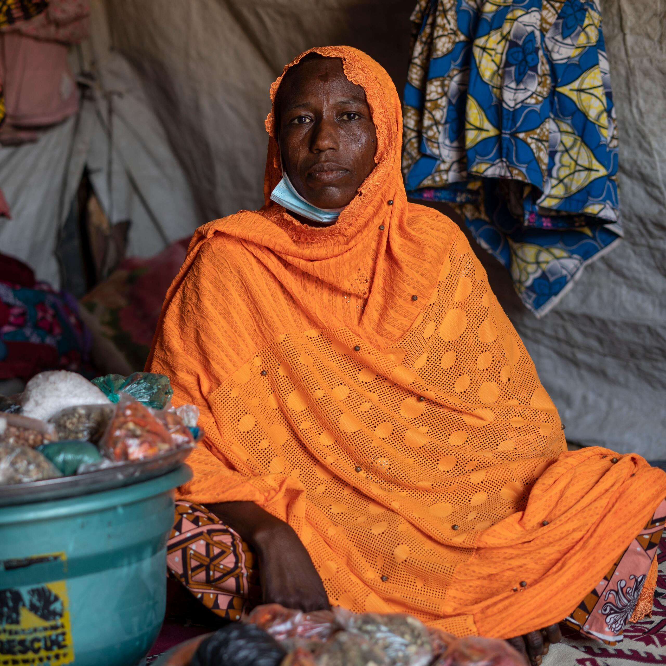 Fandaou Karam sites in a shop in Awaridi refugee camp in Niger next to containers of bagged condiments.