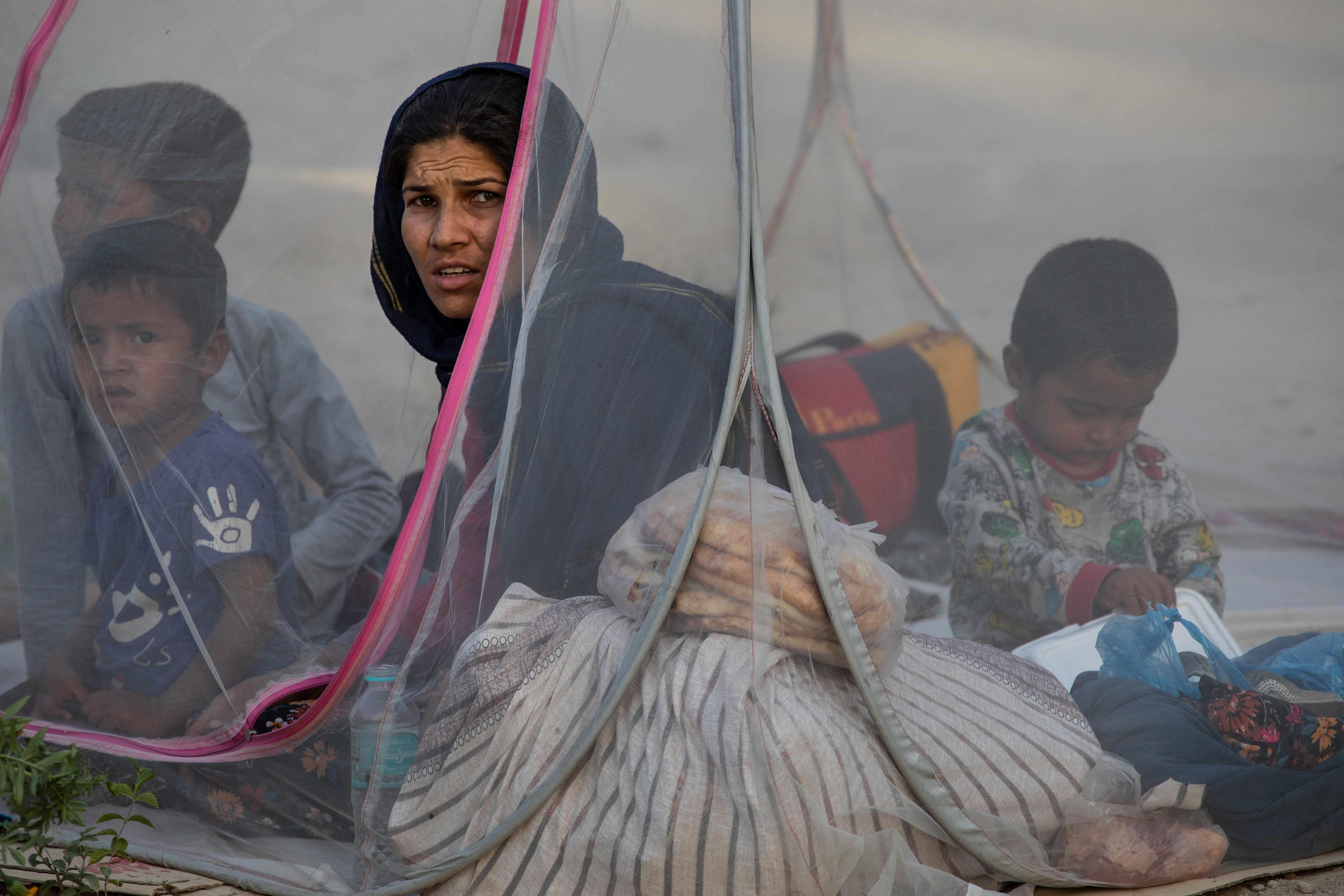A woman sat in a tent with young children.