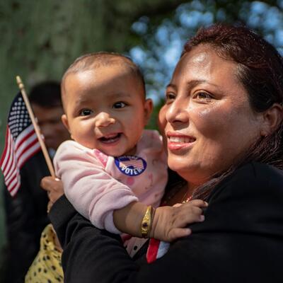 A woman holds an American flag and a baby at a citizenship ceremony in the U.S. 