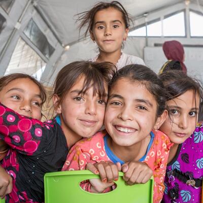Children at an IRC-run program A group of children crowd around the camera and smile