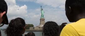 A group of people staring at the statue of liberty.