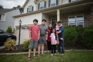 Photo of former Afghan refugee Noori standing outside his house with his family