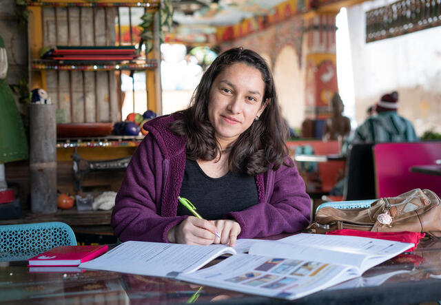 Valentina hält einen Stift in der Hand und sitzt vor zwei Büchen, mit denen sie lernt.