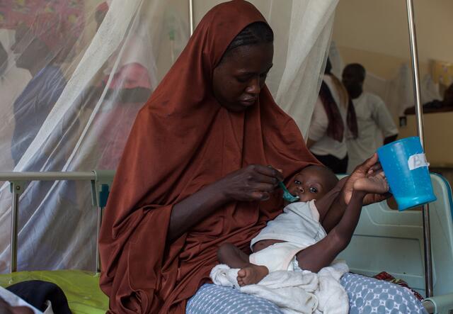 A woman feeding her baby with a spoon