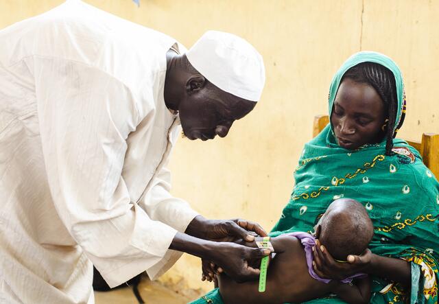 A man meassures the upper arm circumference of y baby