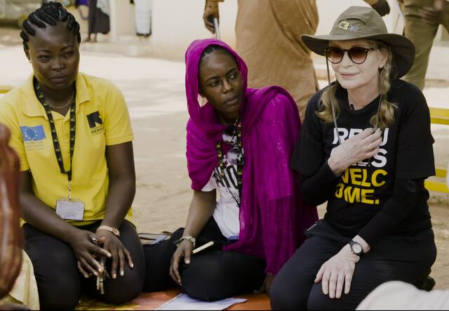 Mia sitting on the ground with two females, on of them a employee of IRC