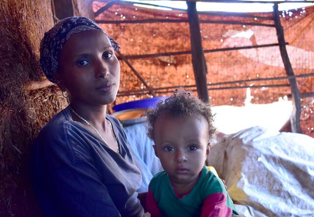 A woman and a young child in a simple tent