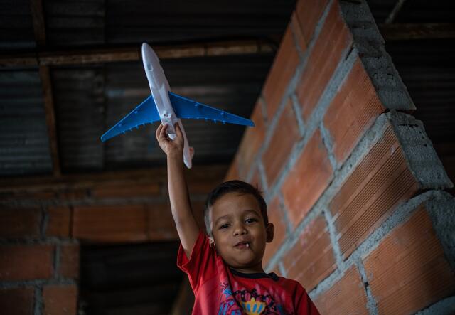 A young boy holding a toy plane in his hands